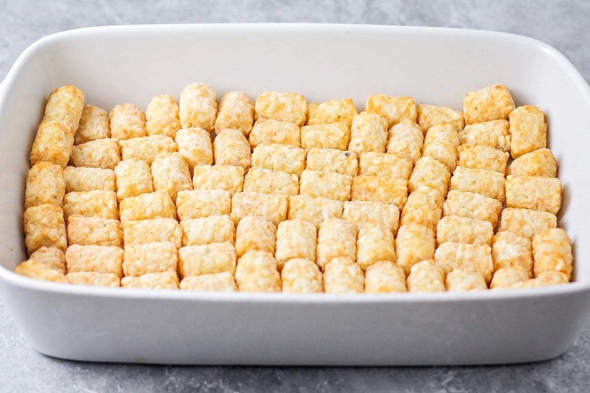 Tater tots layered in a white baking dish.