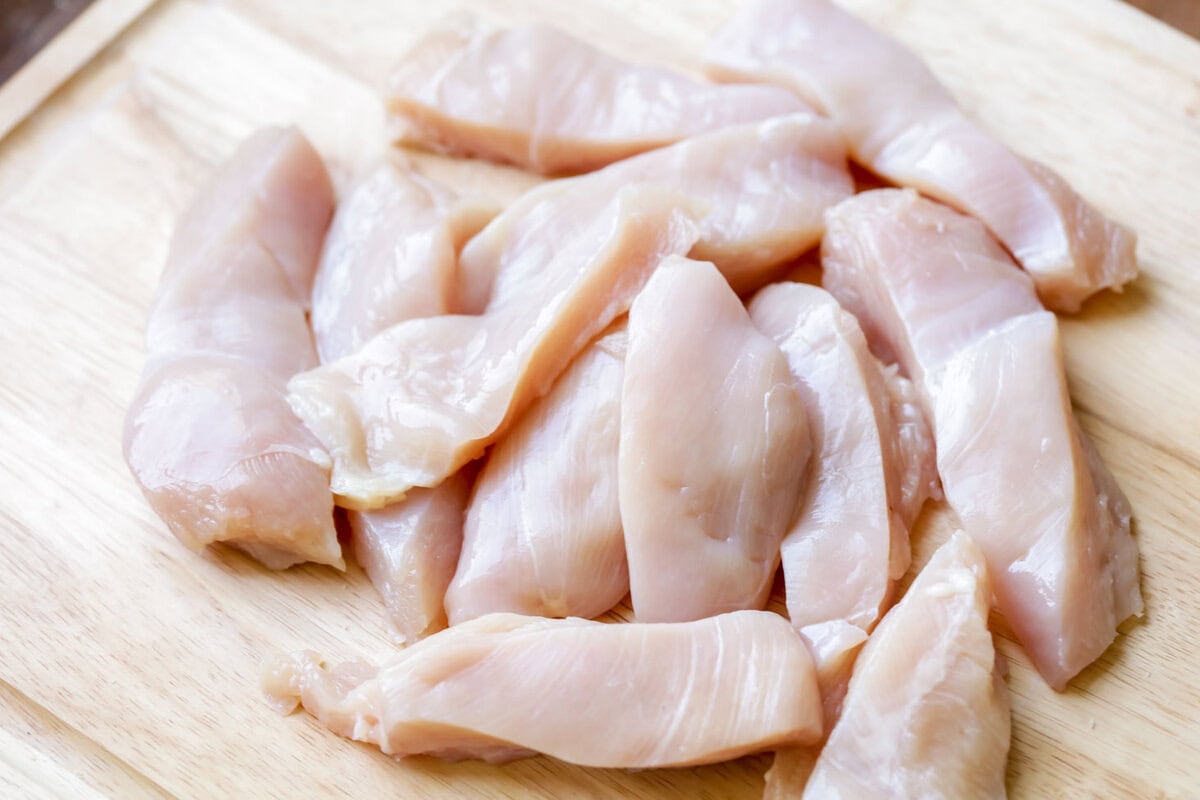 Cut chicken breast strips on a cutting board.