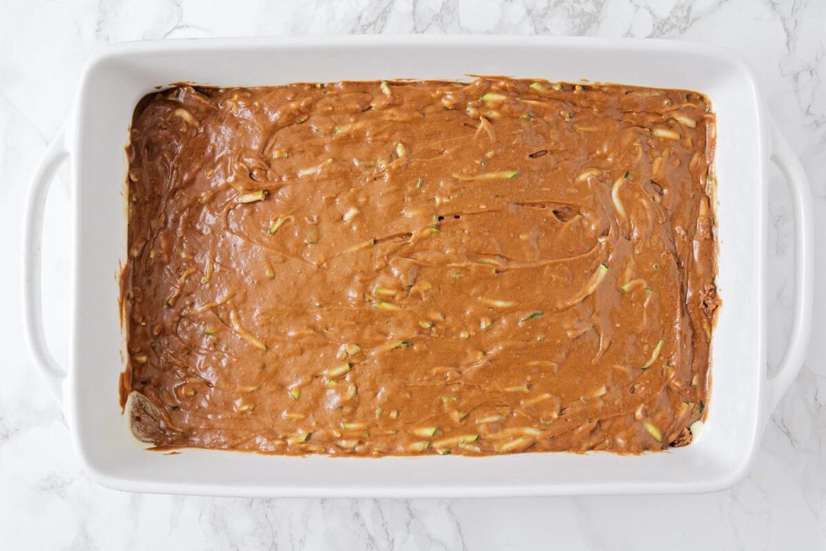 Chocolate cake batter with shredded zucchini in baking dish.