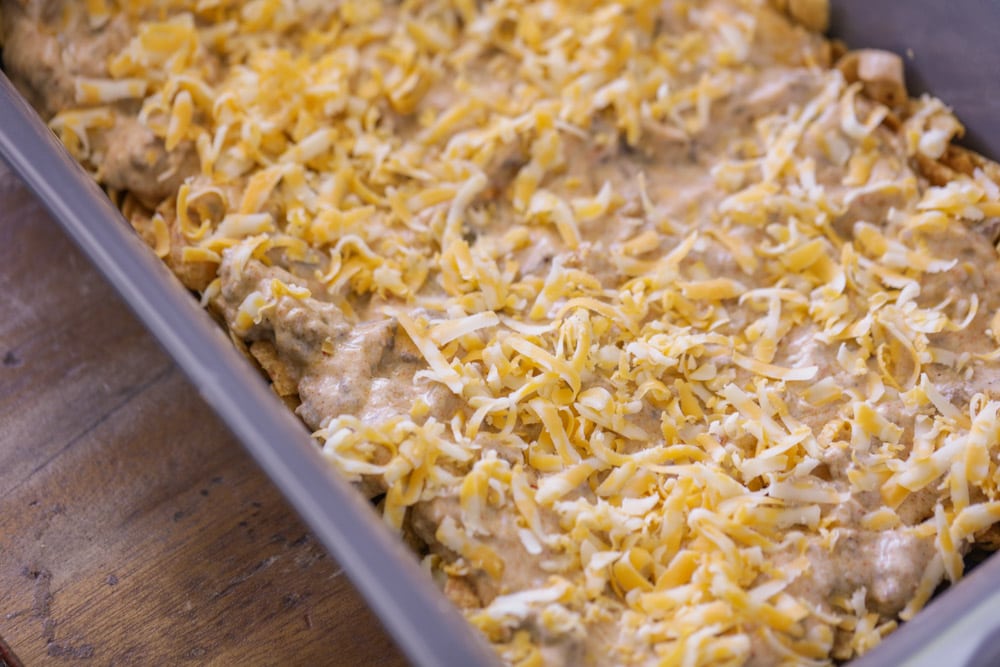 Cheese on top of meat layer and Fritos in baking dish.