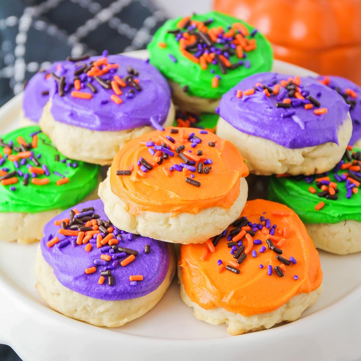 Different color frosted Halloween sugar cookies on cake stand.