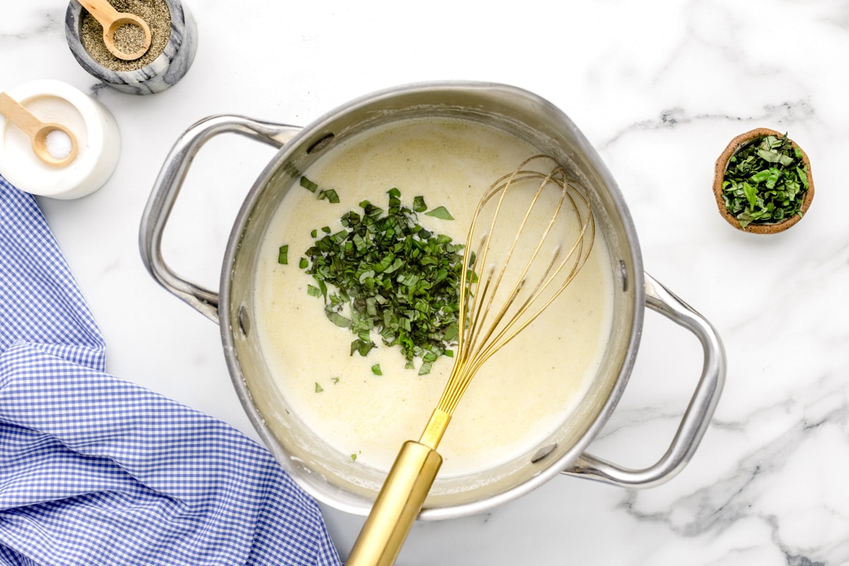 Adding herbs to a pan of white sauce.
