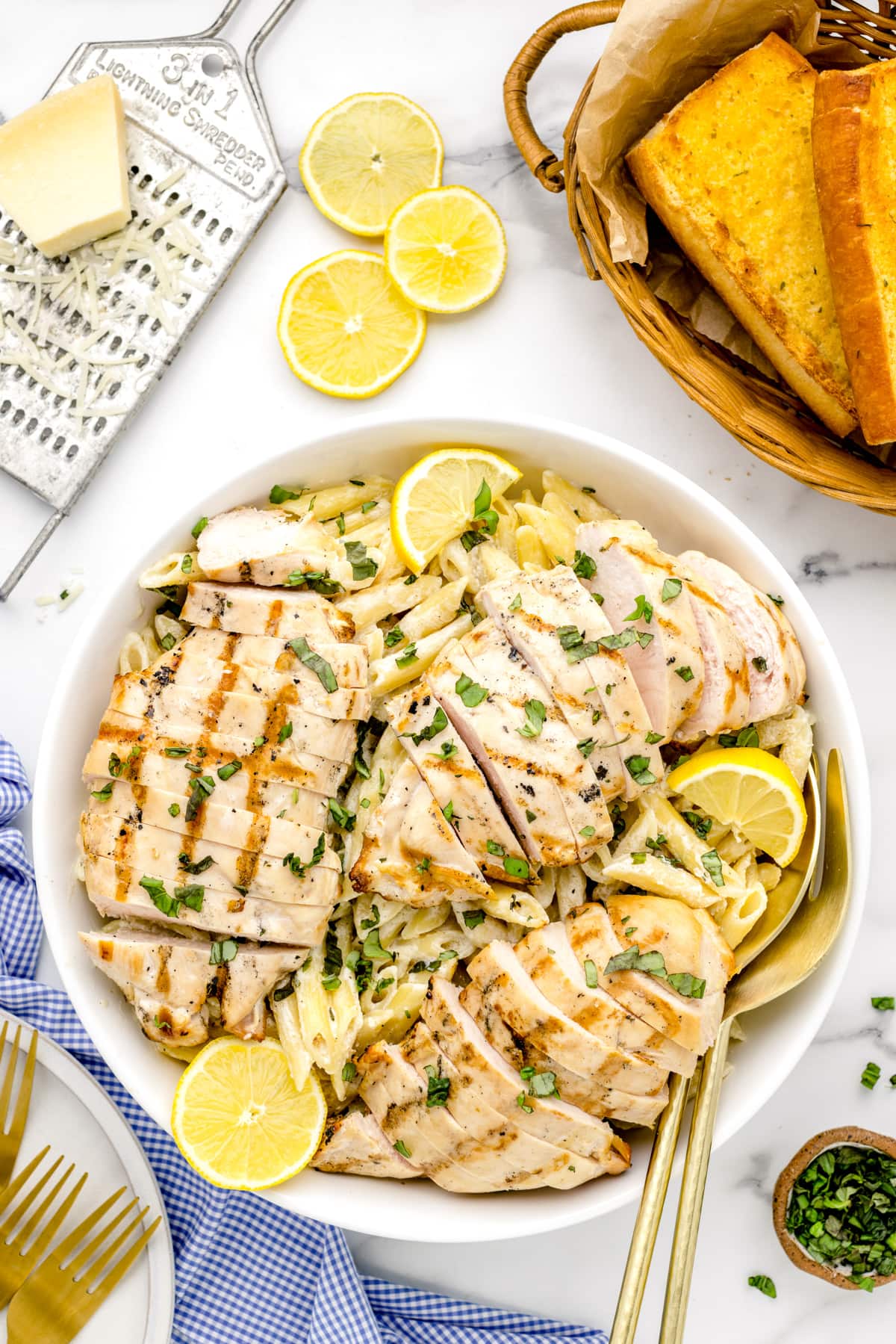 A white bowl filled with lemon chicken pasta served with fresh herbs.