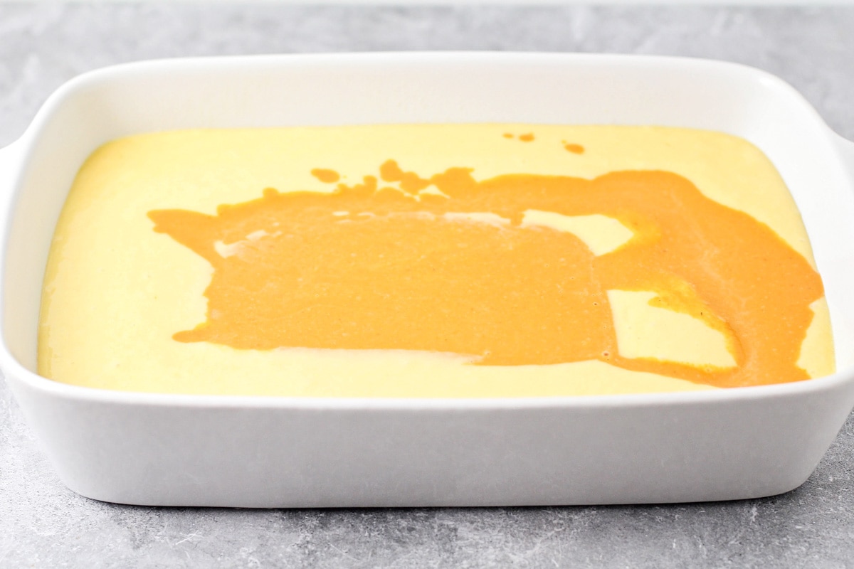 Layering cake batter and pumpkin mixture in a white baking dish.