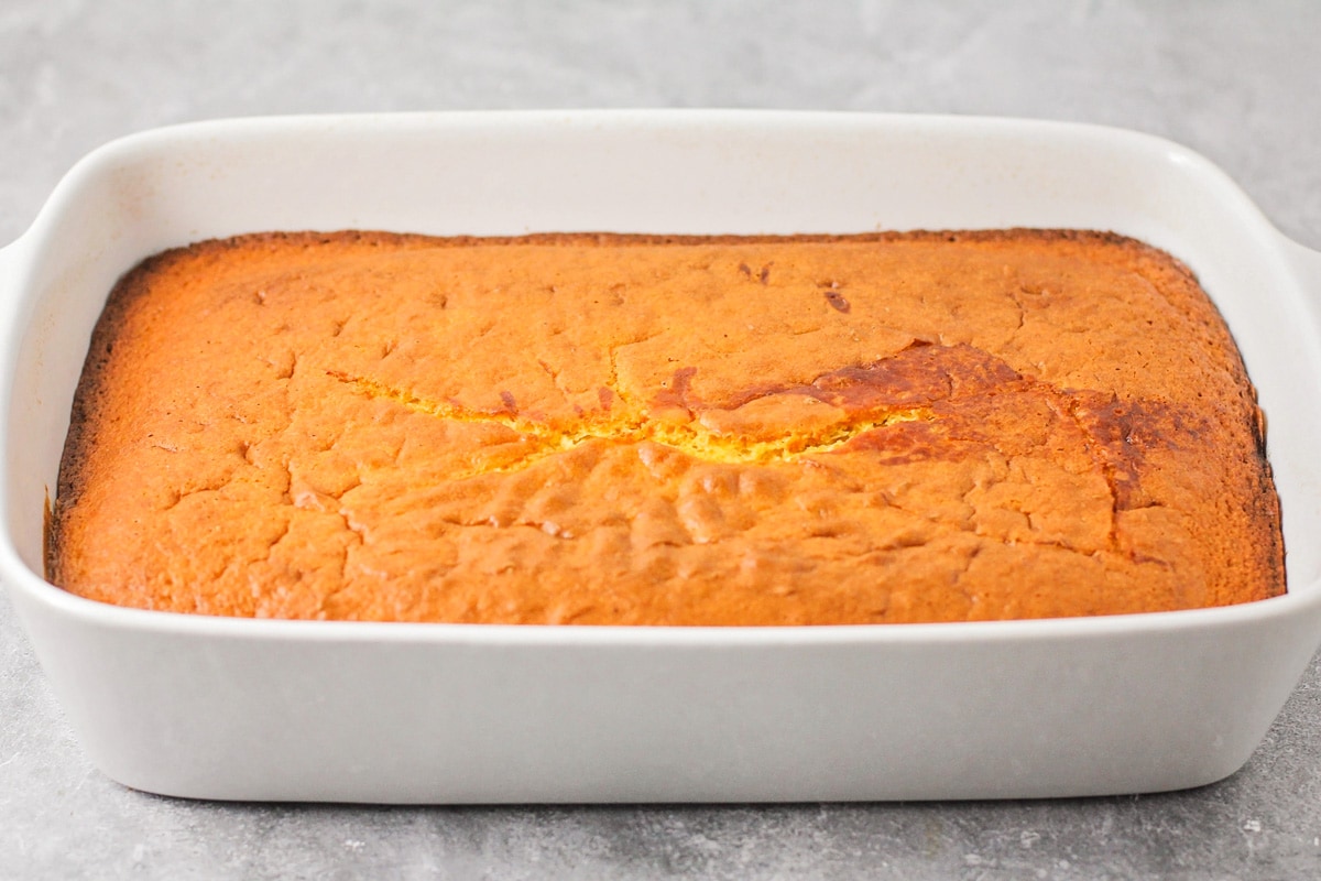 A baked yellow pumpkin cake in a white baking dish.