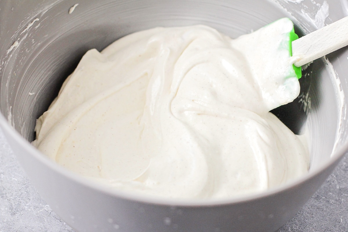 Whipping up a white frosting in a grey bowl.