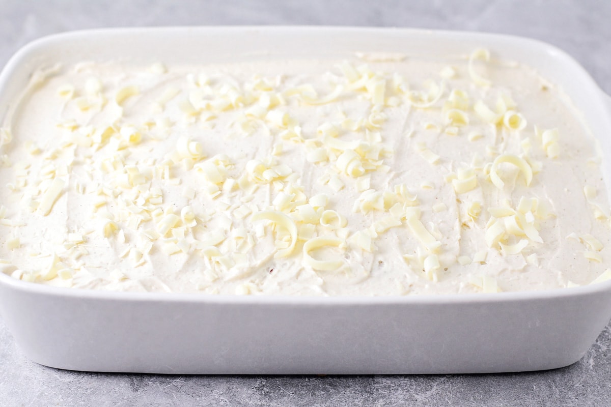 A frosted cake topped with white chocolate shavings.