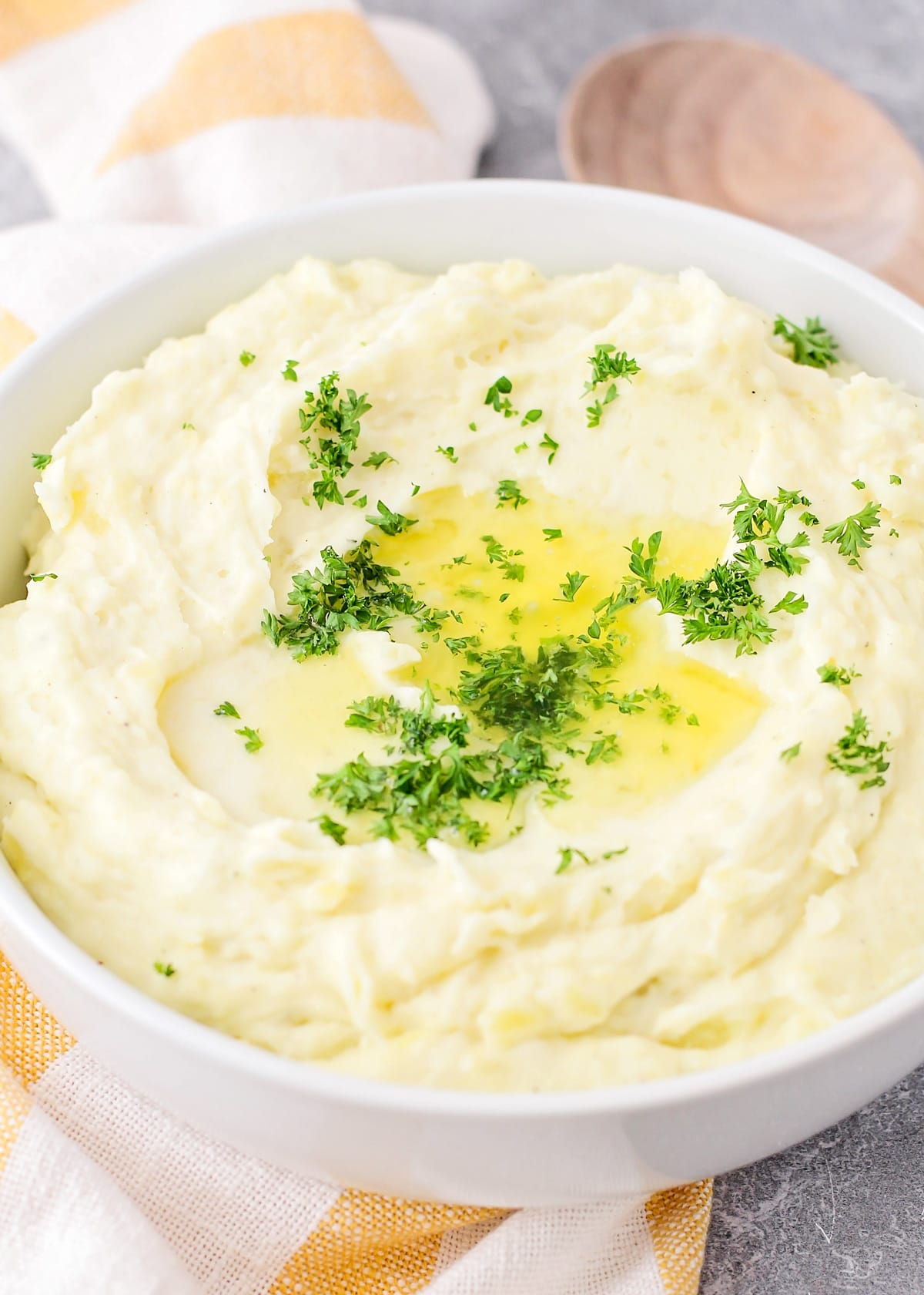 A close up of make ahead mashed potatoes topped with fresh herbs and melted butter.