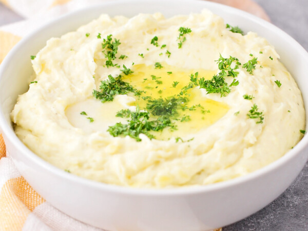 Close up image of make-ahead mashed potatoes recipe served in white bowl.
