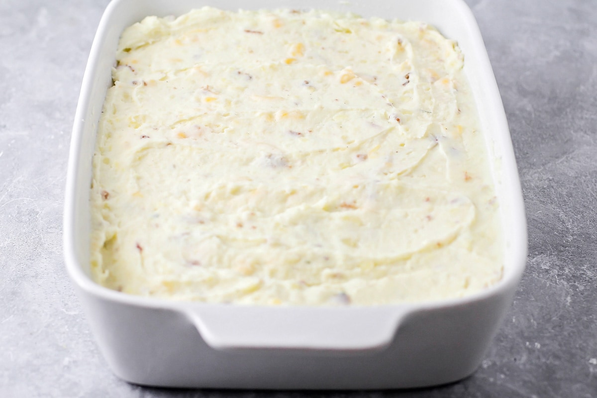 Mashed potatoes spread in a white baking dish.
