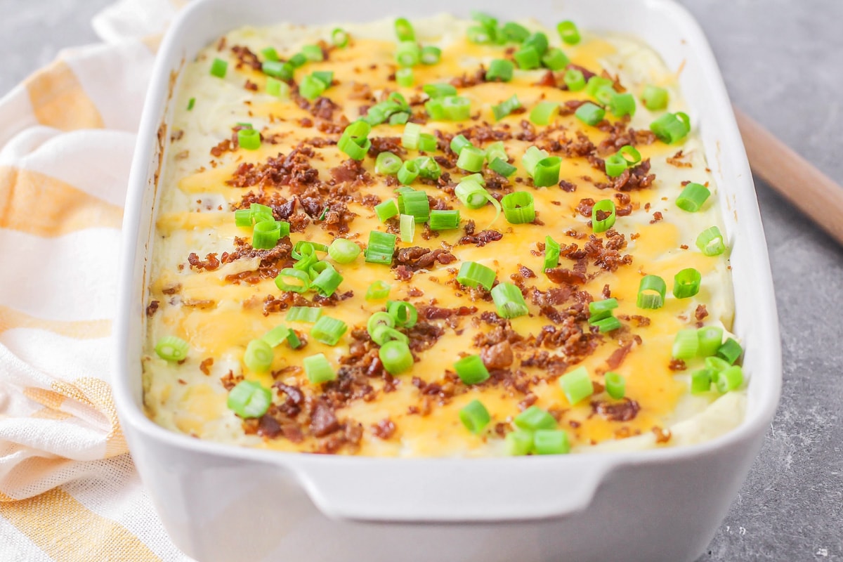 A baking dish covered with cheese, bacon, and green onions.