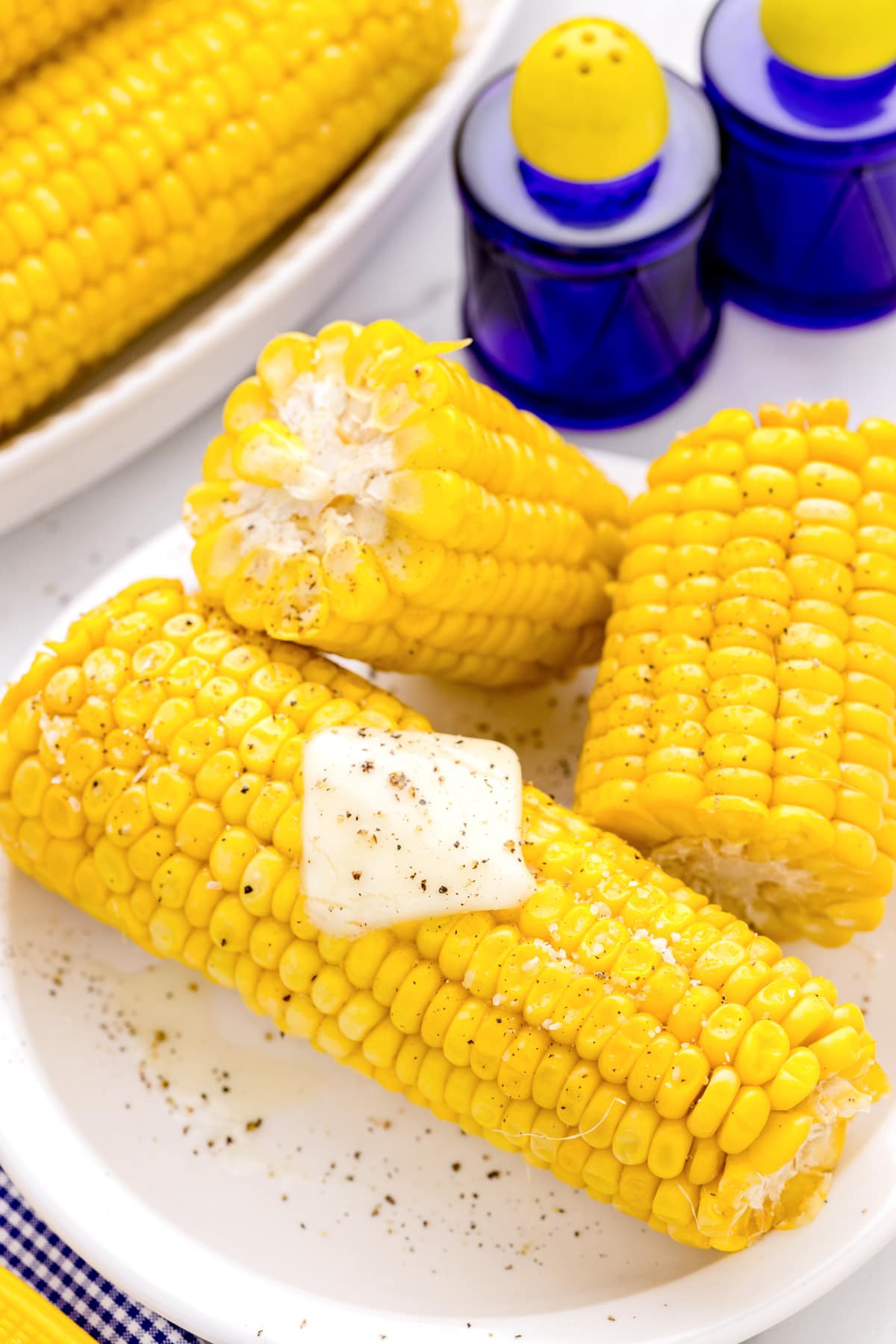 Close up of microwave corn on the cob seasoned with butter and pepper.