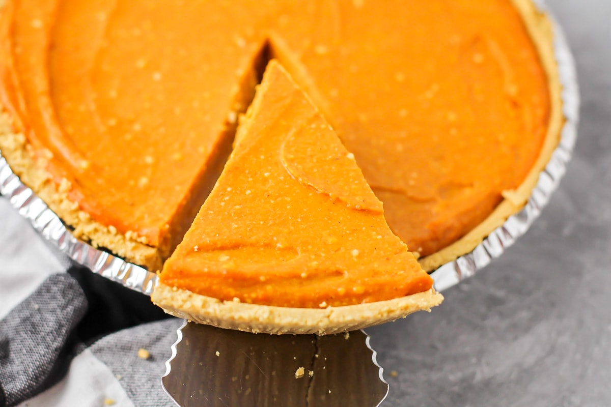 Pulling a slice of pumpkin pie from an entire pie.