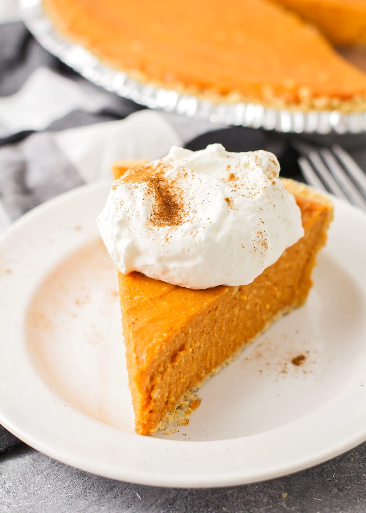 Close up of a slice of no bake pumpkin pie topped with whipped cream.
