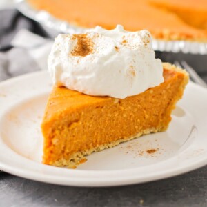 A slice of no bake pumpkin pie topped with whipped cream and spices.