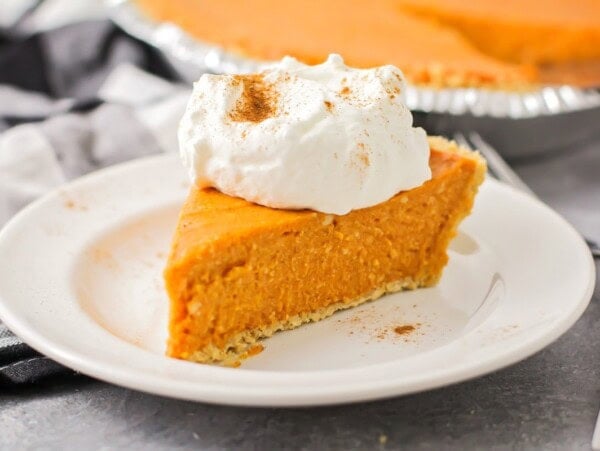 A slice of no bake pumpkin pie topped with whipped cream and spices.