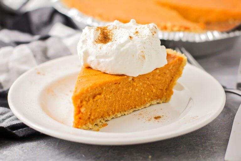 A slice of no bake pumpkin pie topped with whipped cream and spices.