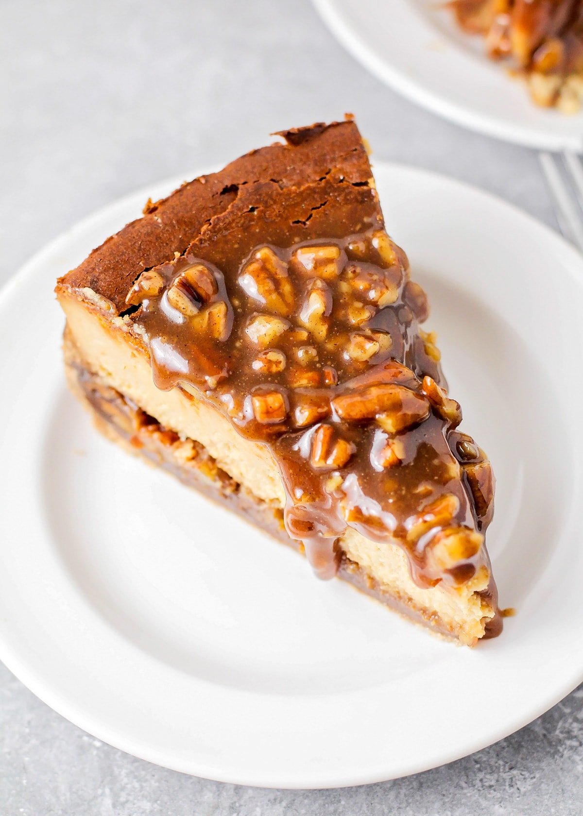 Close up of a slice of pecan pie cheesecake on a white plate.