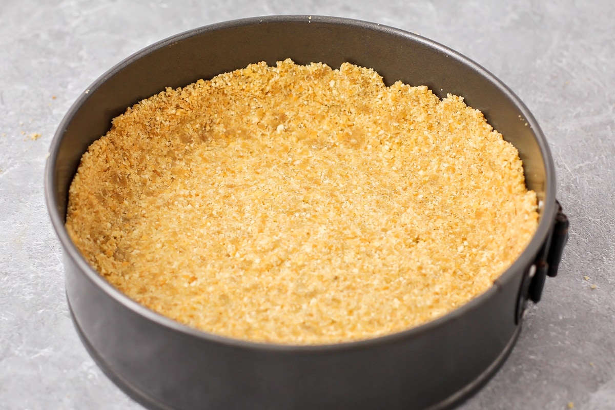 Pressing a vanilla wafer crust into the bottom of a spring form pan.