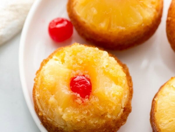 Top view of pineapple upside down cupcakes topped with pineapple and a cherry.