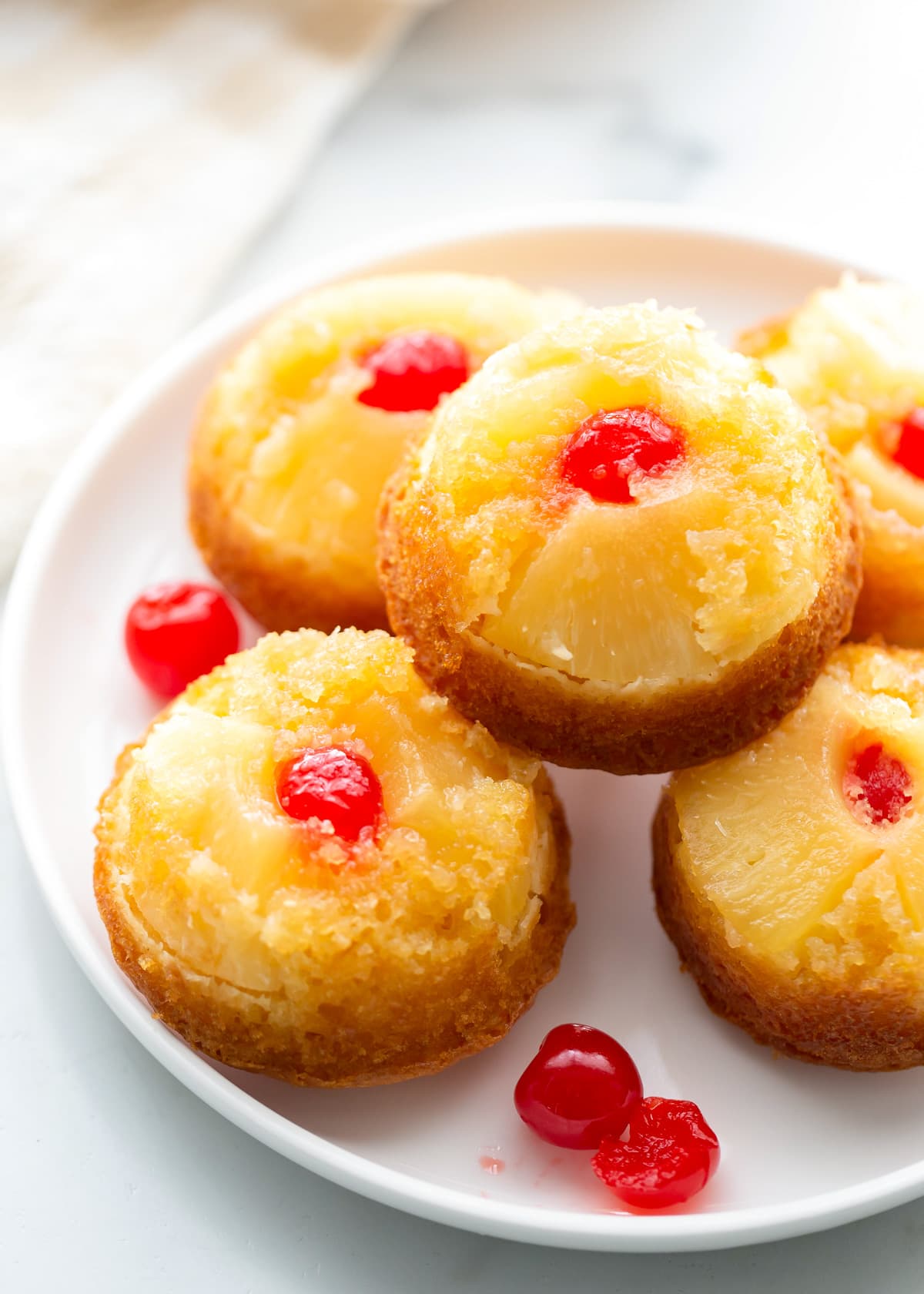 A plate piled with pineapple upside down cupcakes.