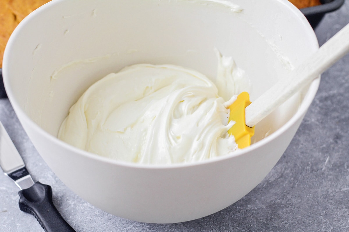 Cream cheese frosting in bowl for pumpkin cake recipe.