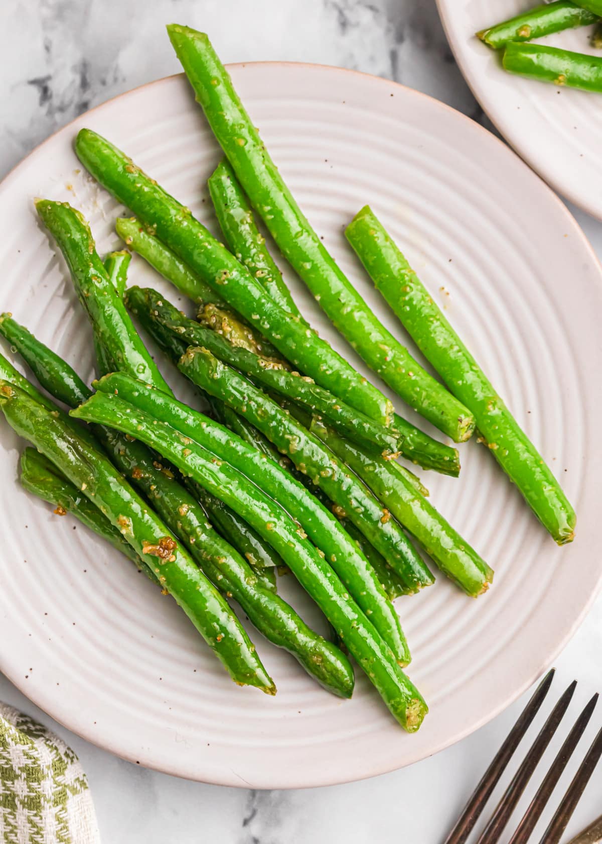 A close up of sauteed green beans on a white plate.