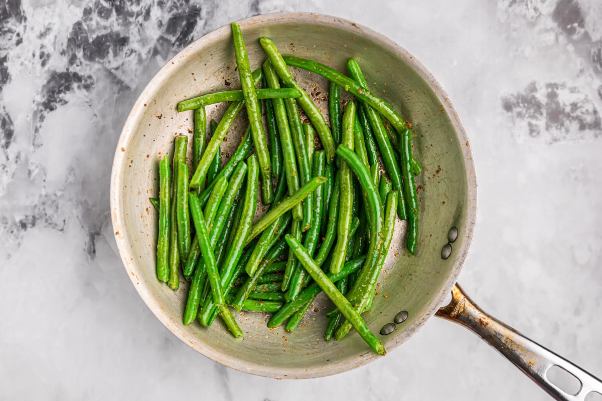 Sauteeing green beans in a pan on the stove.