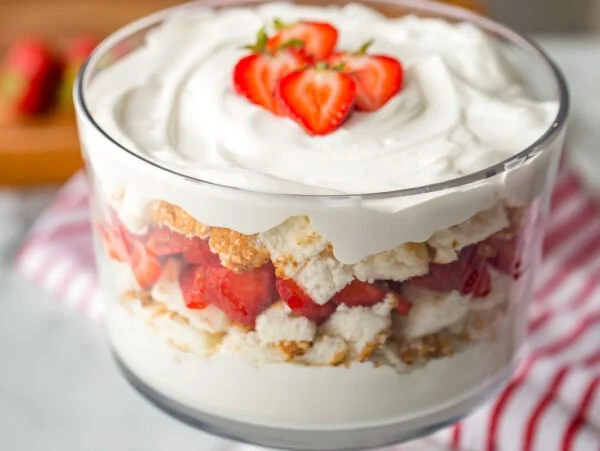 Strawberry shortcake trifle recipe in trifle dish with strawberries on top.