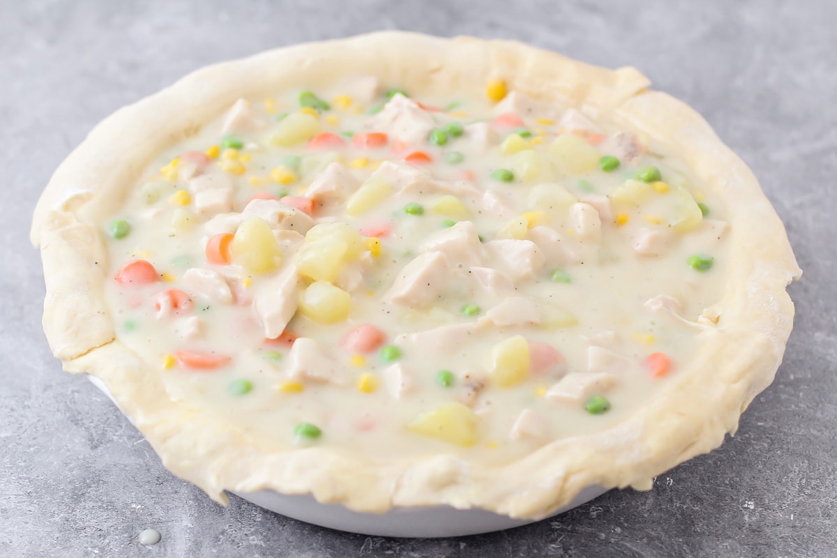 A pie crust filled with veggies, potatoes, turkey, and creamy sauce.