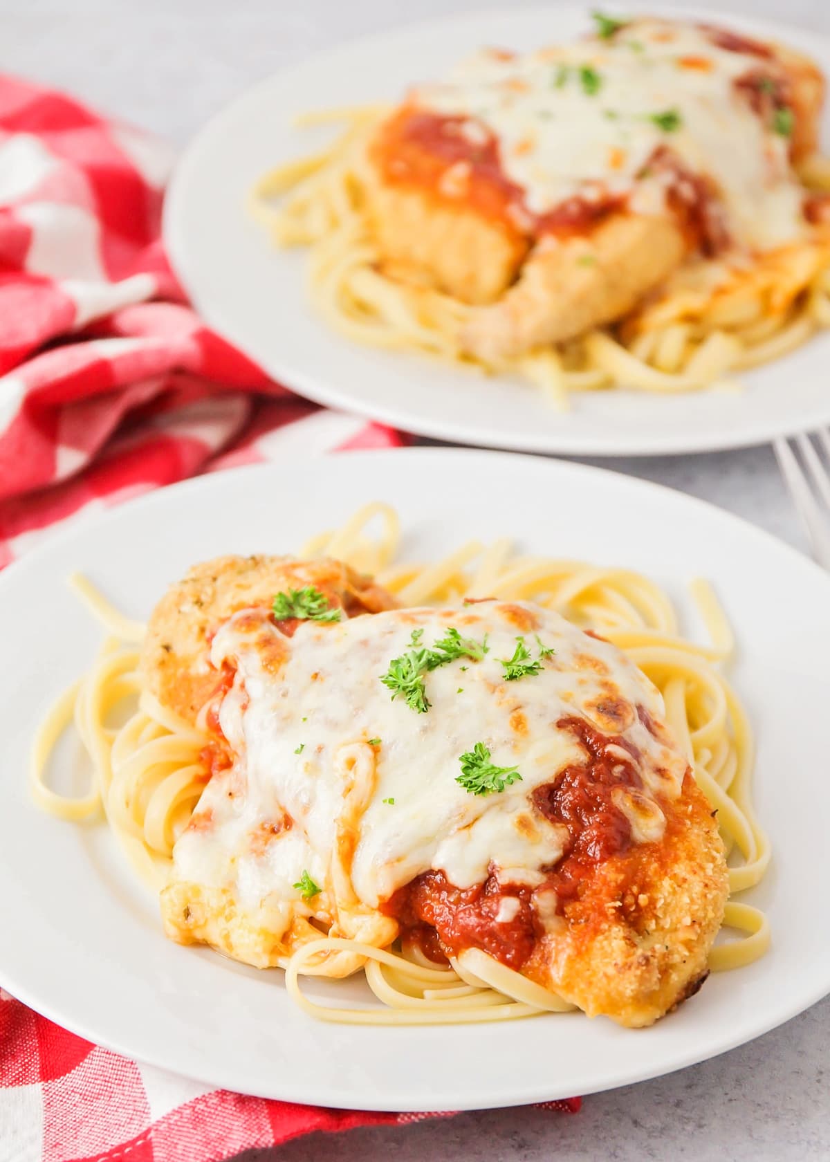 Close up of a plate of chicken parmesan served over pasta.