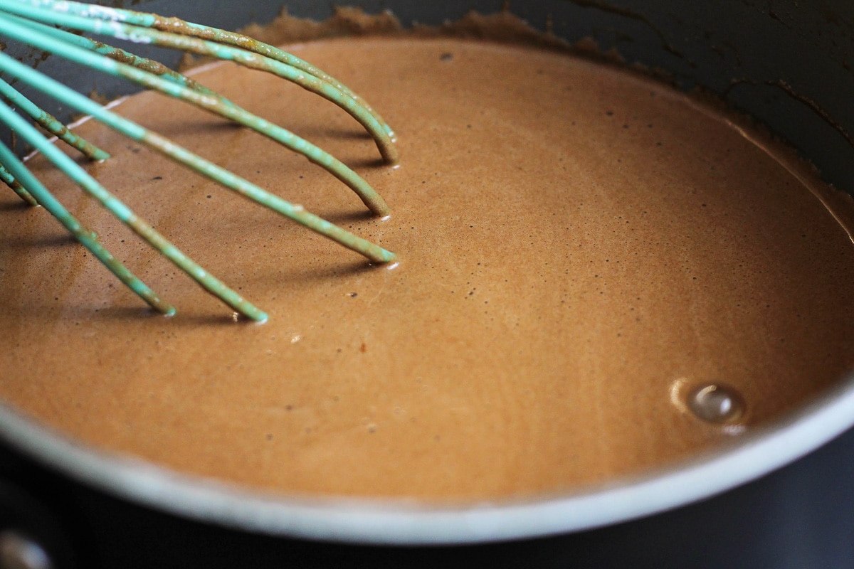 Whisking chocolate custard in a pot on the stove.