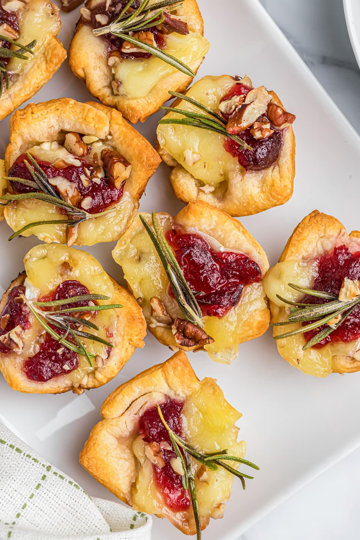 Close up of baked cranberry brie bites topped with rosemary.