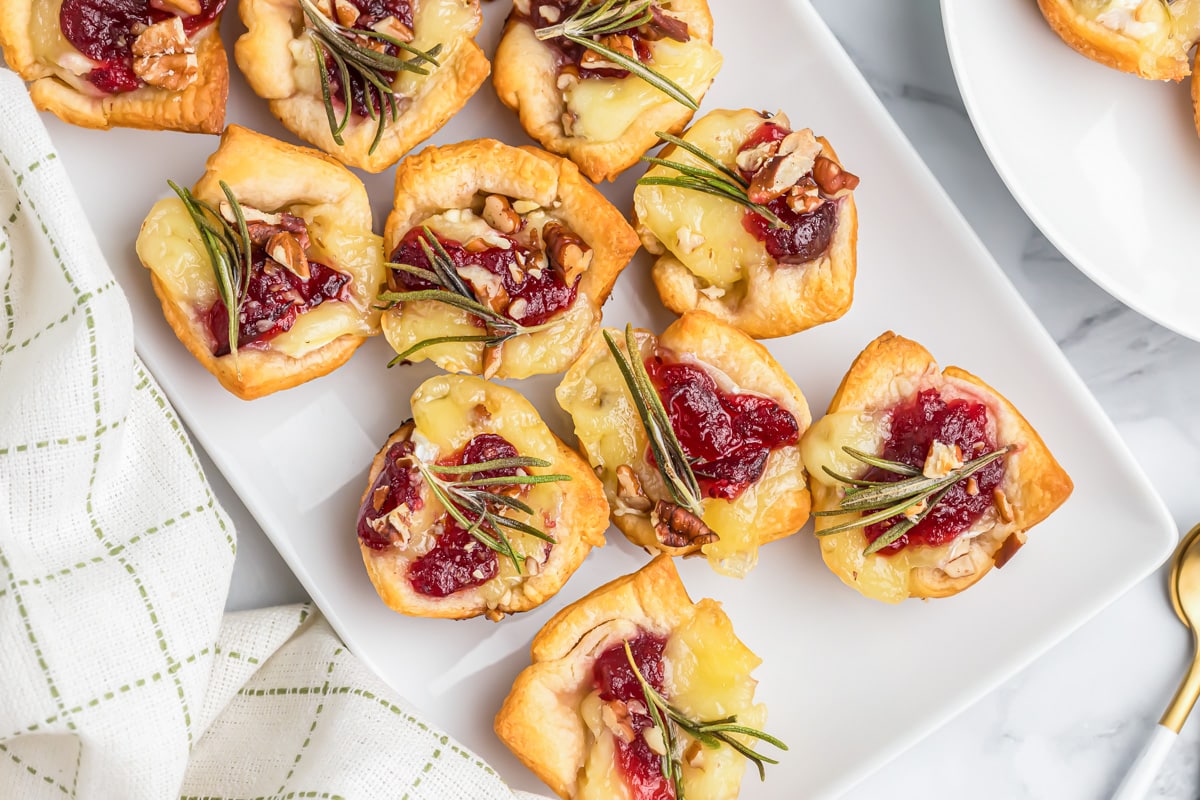 Cranberry brie bites on a white serving platter.