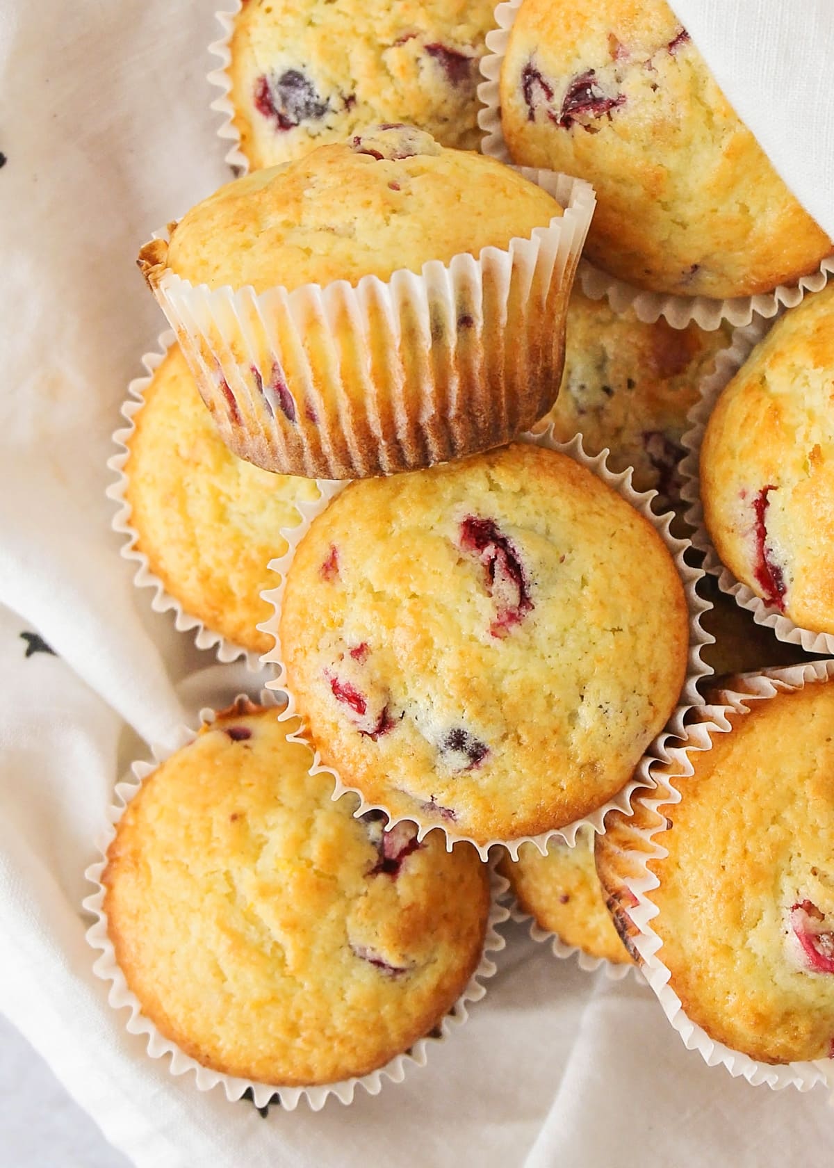 Close up of a pile of cranberry orange muffins in a tea towel.