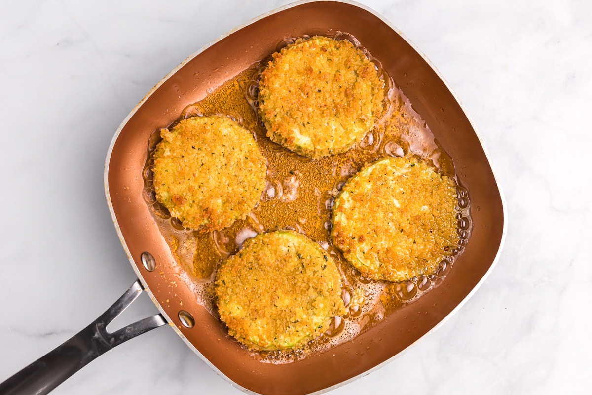 Breaded eggplant frying in a pan of oil.