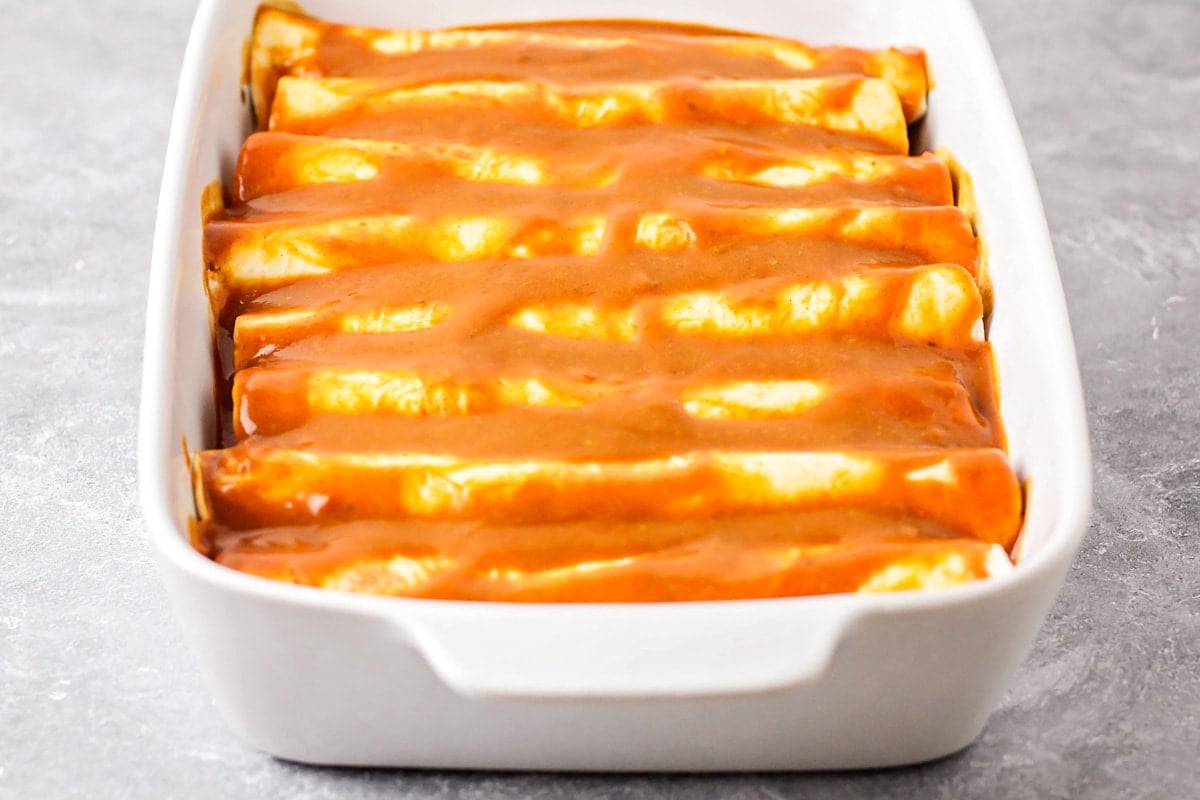 Rolled and filled enchiladas topped with red enchilada sauce.