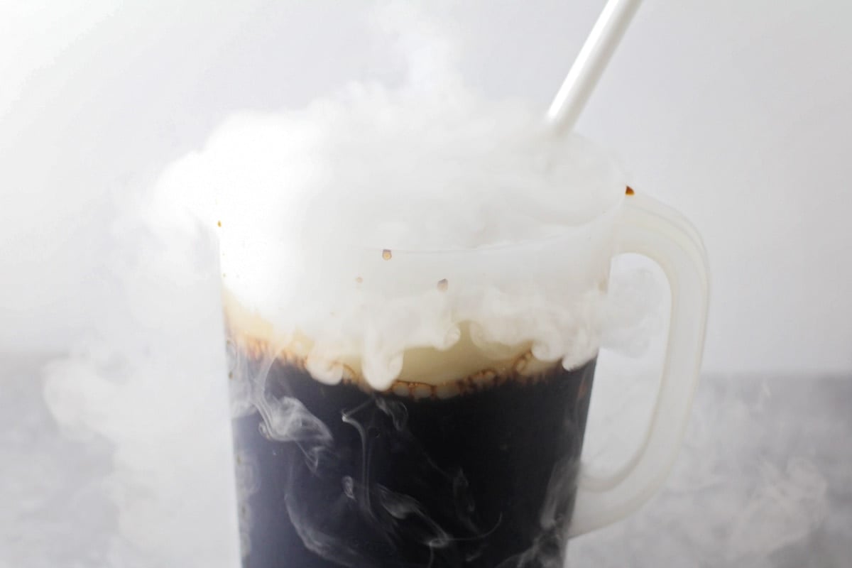 Smoke coming out of a mixture of root beer in a pitcher.