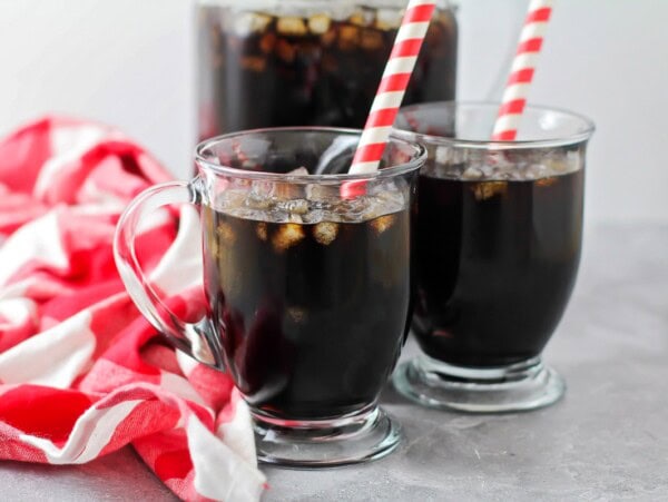 Two glassed of homemade root beer with straws.