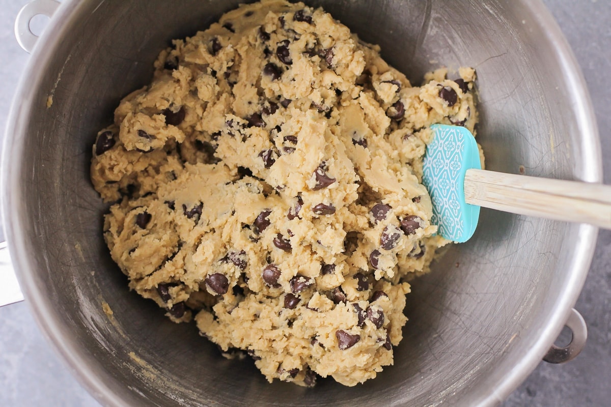 Chocolate chip cookie dough in  metal mixing bowl.