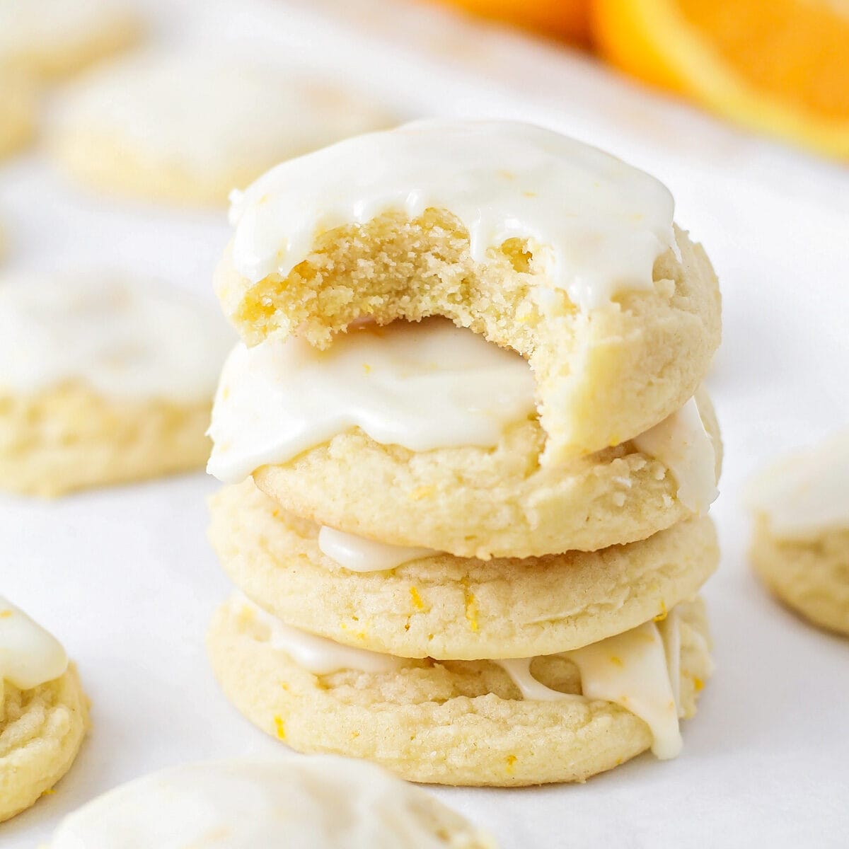 Orange cookies stacked on top of each other with bite taken out.