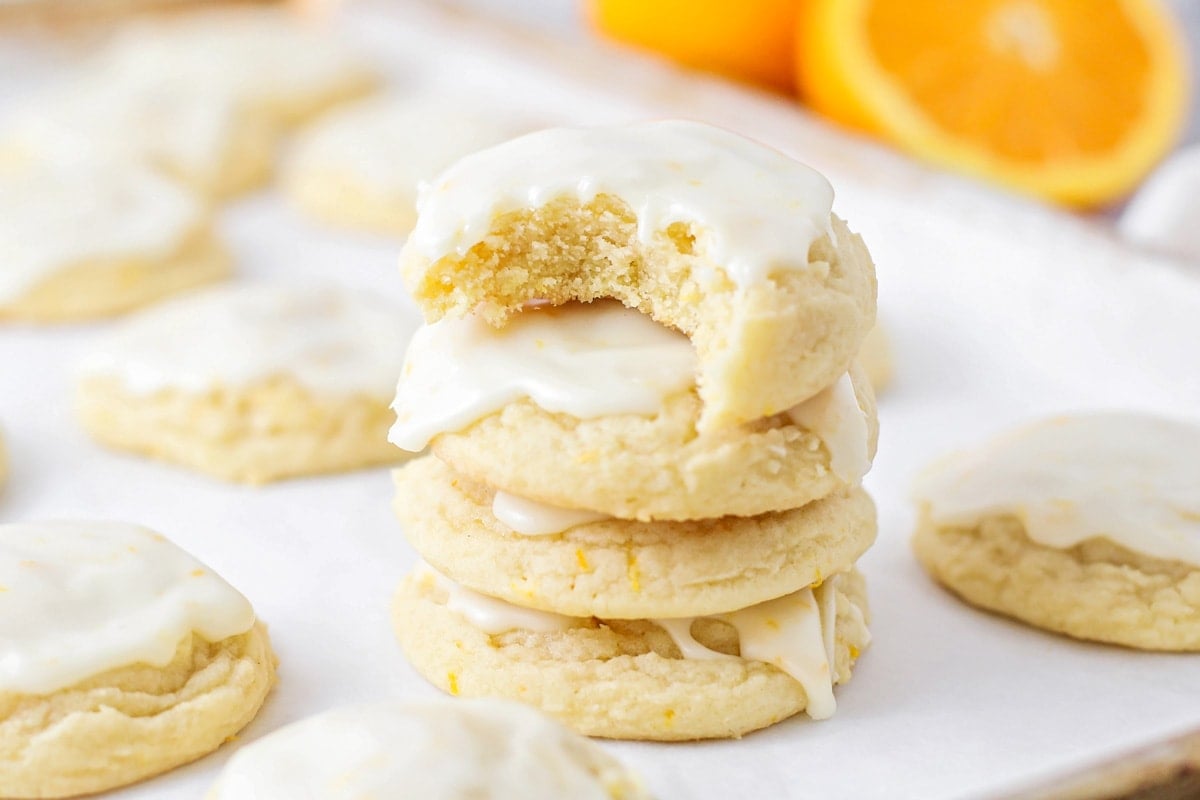 A stack of glazed orange cookies with a bite missing from the top cookie.