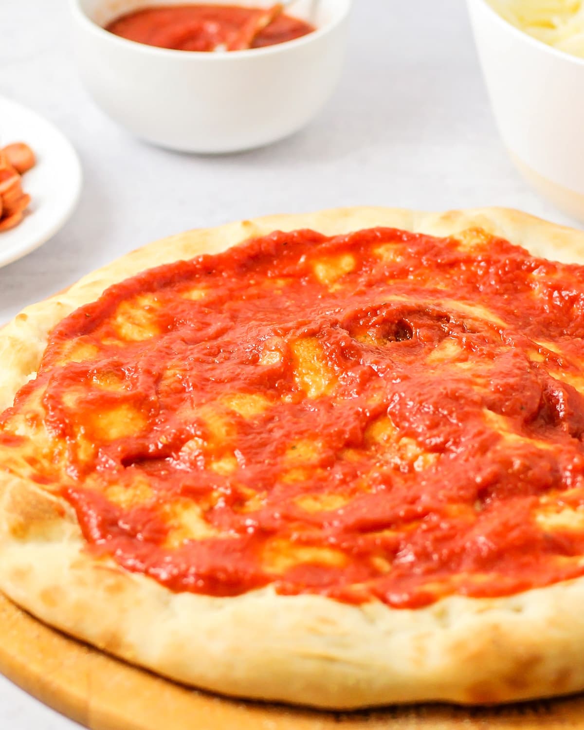 Homemade pizza sauce recipe spread over pizza crust close up image.