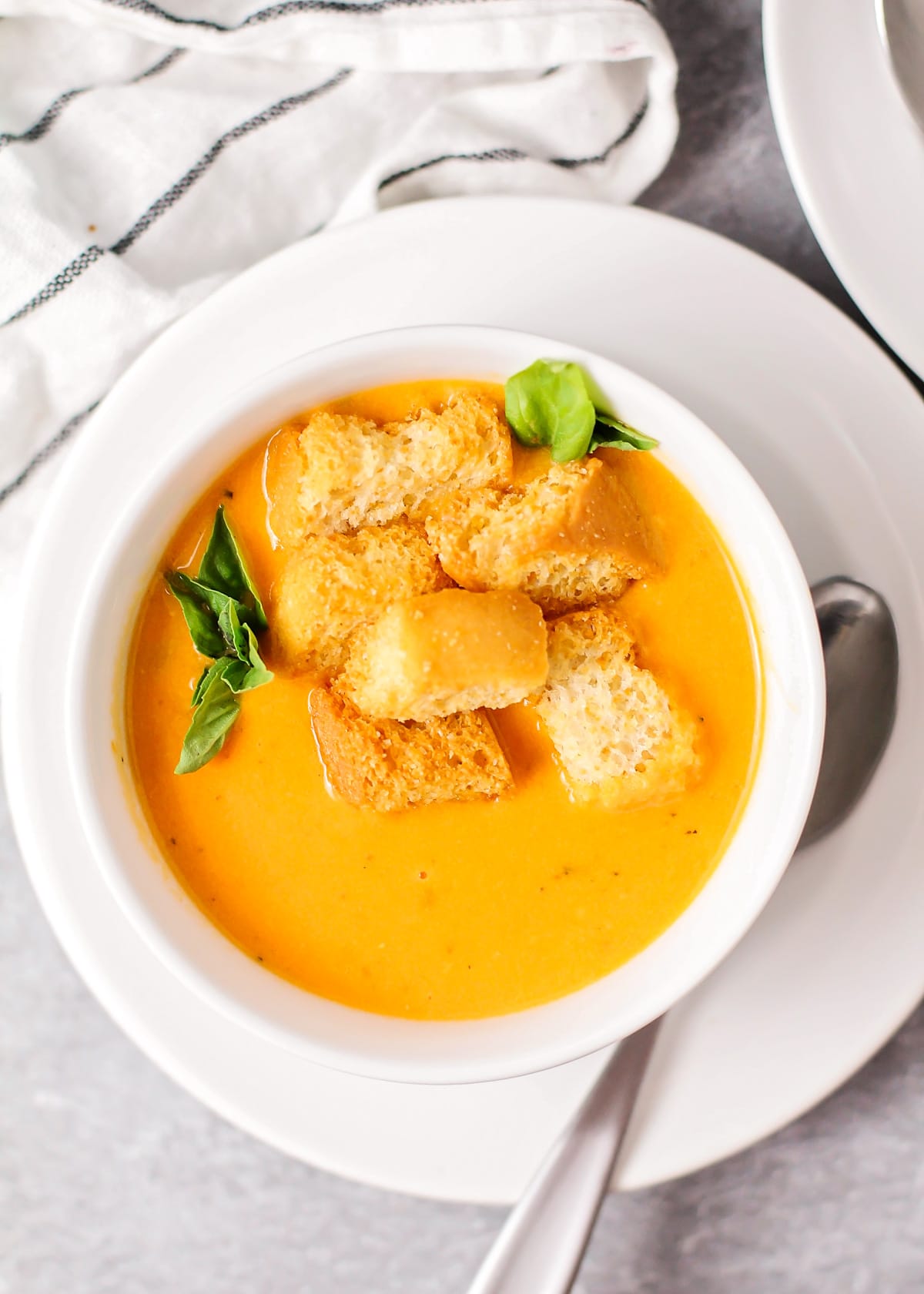 Roasted tomato soup served in a white bowl and topped with croutons.
