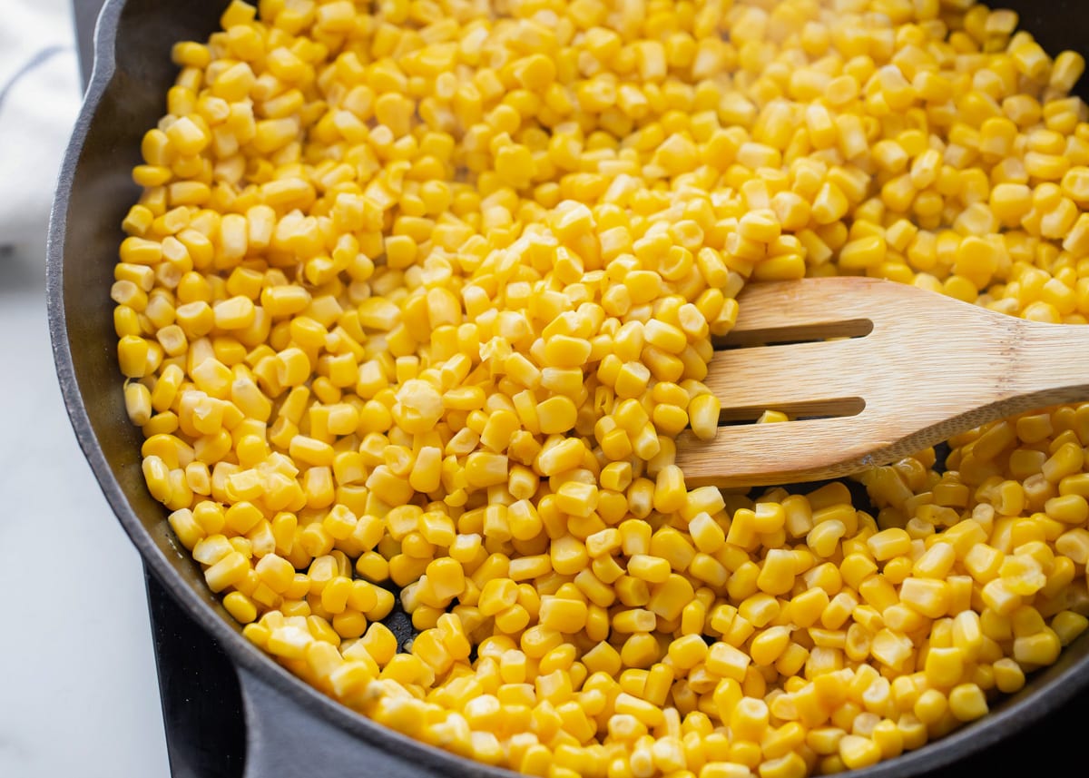 Corn kernels piled in a cast iron skillet.