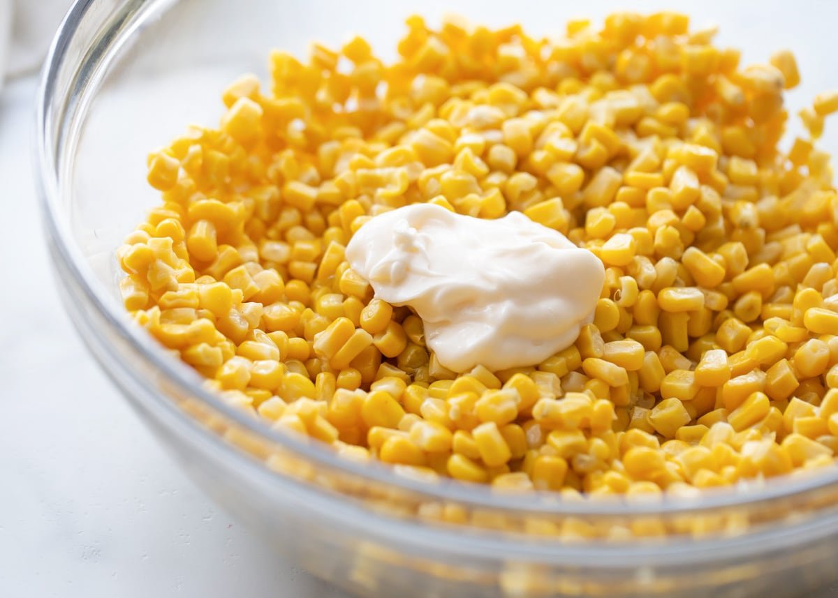 Corn Salad with mayonnaise on top in glass bowl.