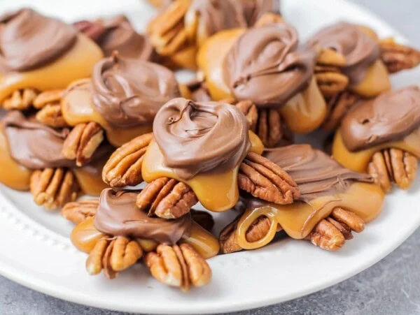 Homemade Turtles Candy recipe - stacked on top of each other on white plate.