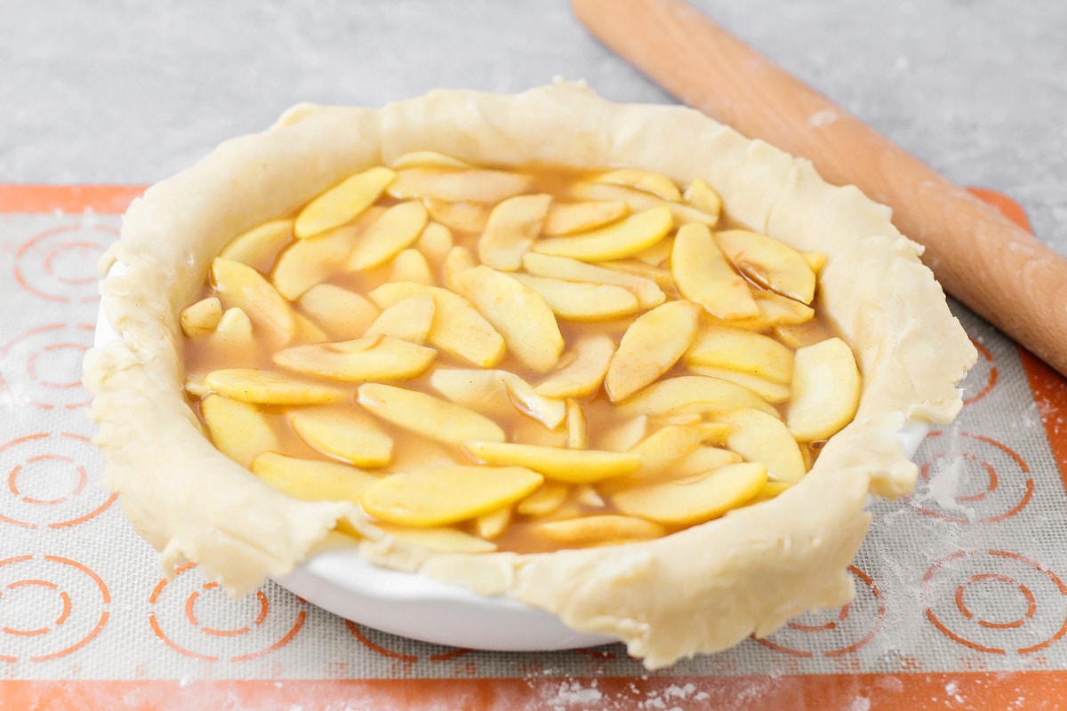 Adding apple filling to the pie crust.