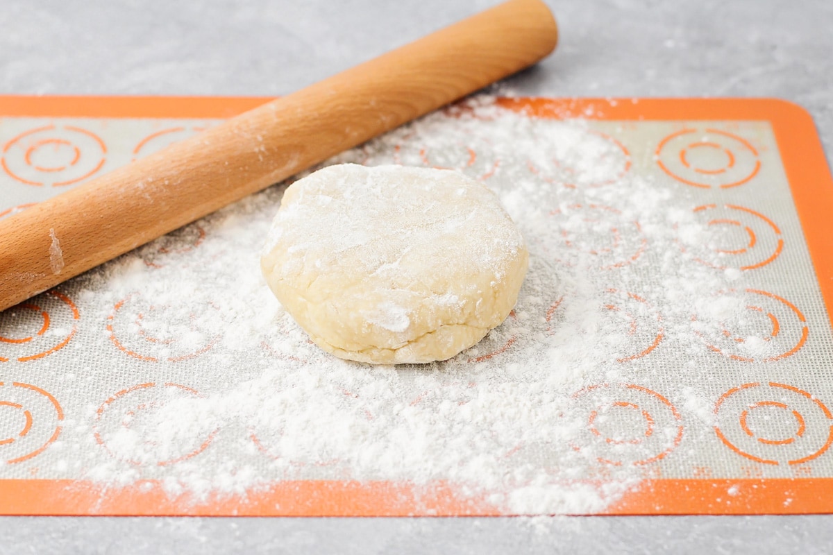 A disc of pie dough on a floured surface.