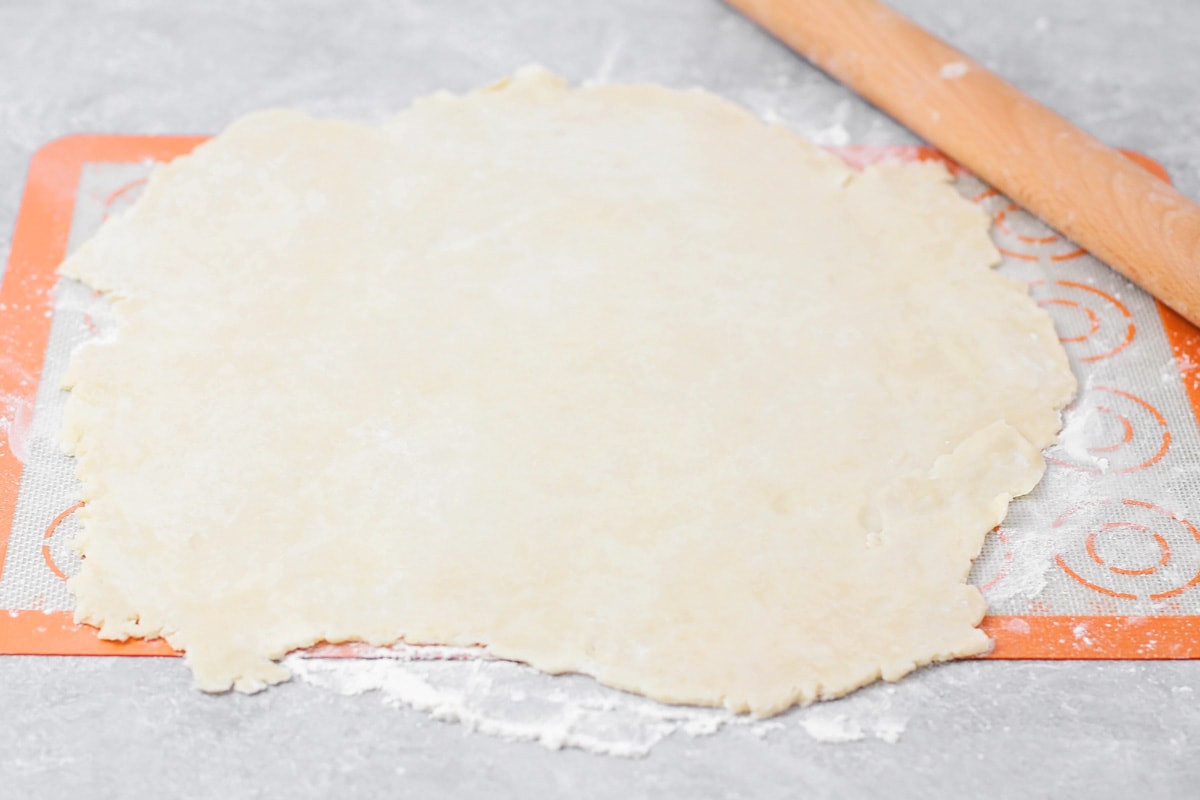 Rolling pie dough out on a floured surface.